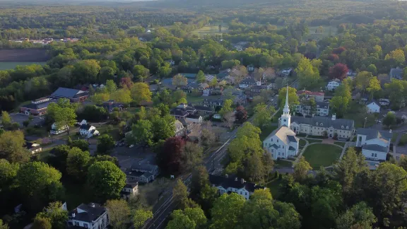 An aerial view over Farmington village center with its white church steeple and wooded hills in Farmington, Connecticut