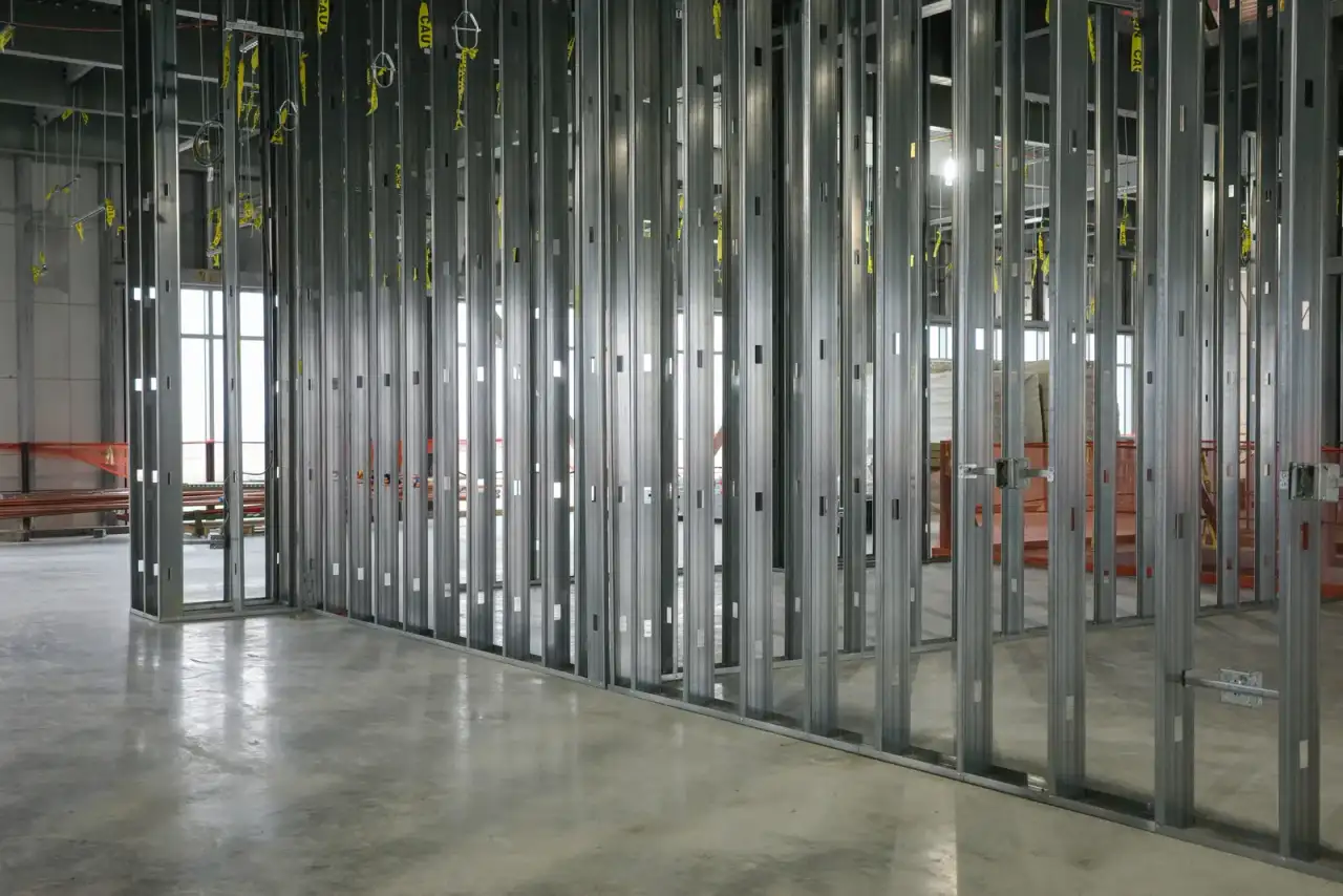 Light-gauge steel-stud partition framing erected in a commercial interior, studs and track in place before the drywall is hung