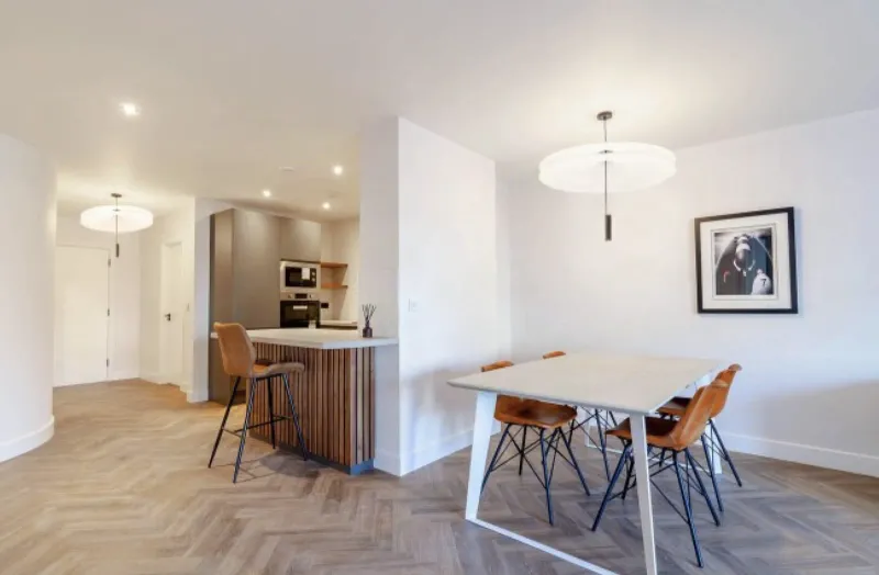 Open-plan apartment kitchen and dining area with finished painted drywall walls and ceiling, recessed lighting, and a pendant fixture