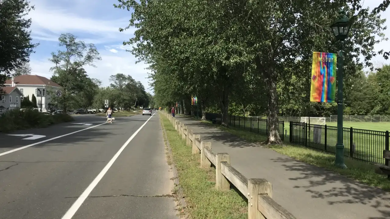 A tree-lined street through the center of Simsbury with a town banner on a lamppost in Simsbury, Connecticut
